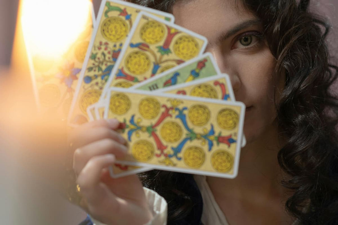 Mulher segurando cartas de tarot próximas ao rosto, sugerindo reflexões e perguntas para fazer no tarot amor